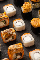 Sushi rolls in rows solid pattern on black background macro