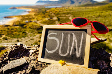 Black board with word sun against sea coast