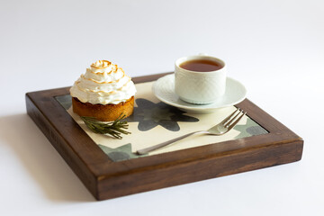 Cake with white cream and a cup of tea on a tray