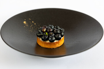 cake with fresh berries, blueberries on a black plate