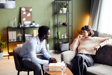 Psychologist talking to young woman in private therapy session