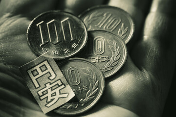 手のひらの上の日本円の硬貨と円安イメージ (モノクローム）