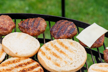 Homemade crispy fried hamburger patties on the grate of a charcoal grill over glowing coals with...