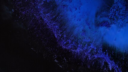 Neon blue purple dark colors ink and shiny particles macro. Liquid abstractions. Abstract painting texture. Colorful amazing organic background. Fluid art. The universe, the cosmos