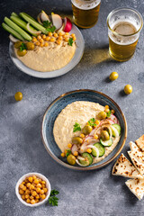 Hummus. two bowls of homemade hummus garnished with chickpeas, olives, parsley and cucumbers, flat lay, middle east food