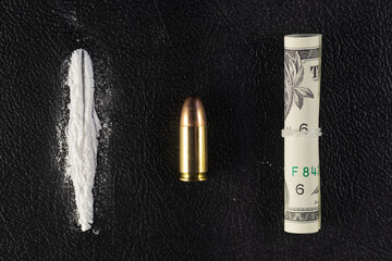 A line of cocaine powder, a single 9 mm bullet and dollar bill scroll. Conceptual mockup of illegal drug dealing, trafficking, war on drugs.