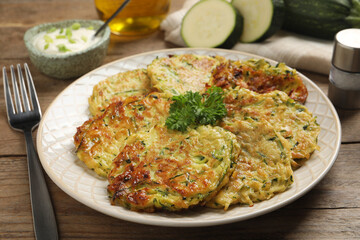 Delicious zucchini fritters served on wooden table