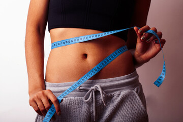 woman measuring waist with tape on knot, african tan isolated