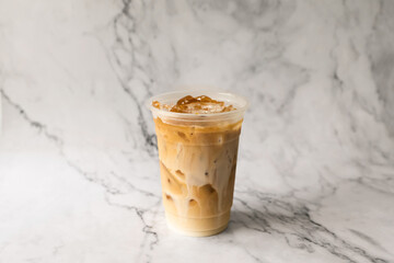 Iced latte coffee on plastic cup place marble background