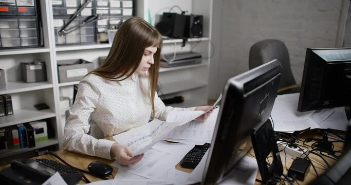 In the office. A young woman seriously looks at documents and then freaks out and throws them on the table. She looks tired. On the table is a mess. Slow motion 4k footage