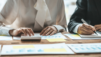 A desk in a company conference room has a group of business people attending and with supporting documents laid out, brainstorming sessions to fix and plan the company's growth. Business meeting idea.