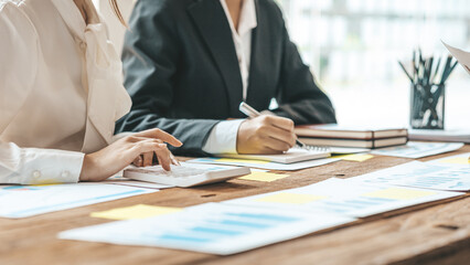 A desk in a company conference room has a group of business people attending and with supporting documents laid out, brainstorming sessions to fix and plan the company's growth. Business meeting idea.