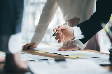 A desk in a company conference room has a group of business people attending and with supporting documents laid out, brainstorming sessions to fix and plan the company's growth. Business meeting idea.