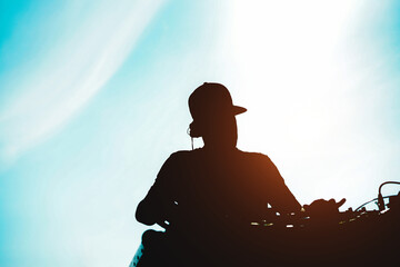 Silhouette of dj mixing outdoor during summer vacations at sunset time - Focus on head