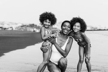 African sister twins having fun with mother on the beach - Main focus on mom face - Black and white...