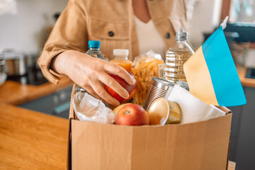 volunteer packing the paper box with groceries and necessary things for Ukraine people 