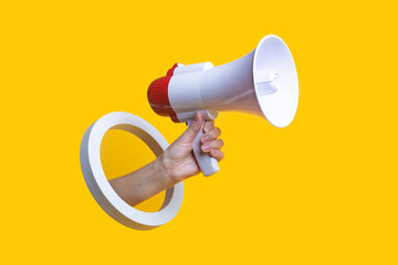 Female hand holds a megaphone in a round hole on a yellow background. - obrazy, fototapety, plakaty
