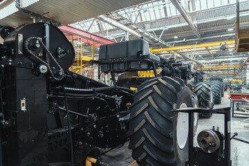 Conveyor line for production and assembly of large industrial machines, tractors or combines with big rubber tires in factory.