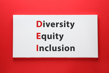 Paper with abbreviation DEI - Diversity, Equity, Inclusion on red background, top view