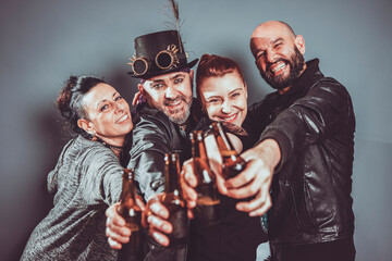 four friends toast to camera with their beers with positive attitude looking at camera in studio shot on gray background