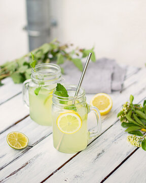 Two mugs with lemon and lime lemonade on white table