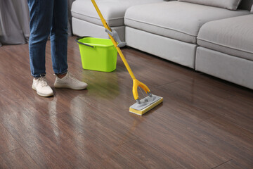 Woman cleaning parquet floor with mop indoors, closeup