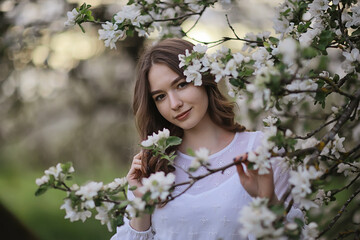 Fototapeta premium springtime fashion portrait of a young girl in a blooming cherry garden, tenderness of the morning