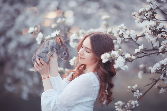 easter bunny in the hands of a beautiful girl, spring, april in a blooming garden, portrait of a woman