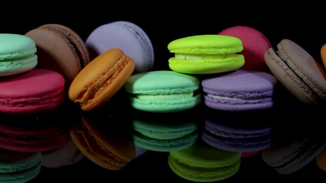 Lots of colorful macaroons on black background with reflection. Traditional french dessert