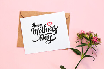 Flowers with envelope with greeting card on pink background