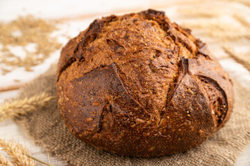 Fresh homemade golden grain bread with ears on white, side view, selective focus.