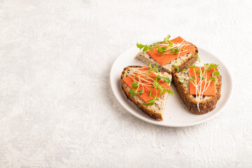 Grain bread sandwiches with red tomato cheese and microgreen on gray, side view, copy space.