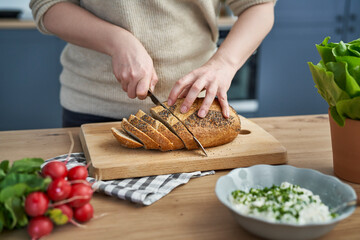 Close up of woman cutting bread in slices for sandwiches