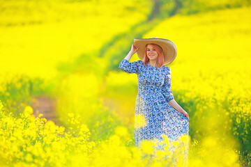 Fototapeta na wymiar Girl in a long vintage dress hat in a field of flowers, happy summer sunny freedom female