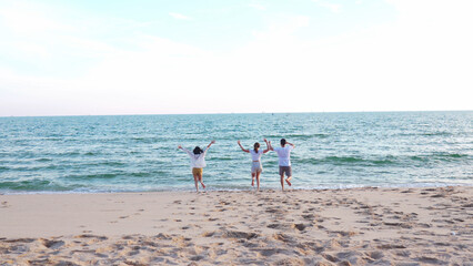 Young  asian girl holds her friends hand running into the sea, friends having fun in sea waves at beach, enjoying with travel and resting on summer vacation or holiday concept.