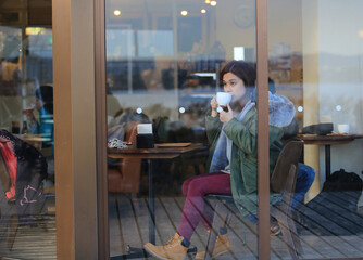 woman take a Coffee break and watch through the window in cafe
