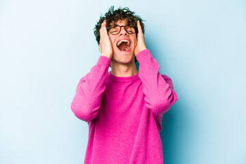 Young caucasian man isolated on blue background laughs joyfully keeping hands on head. Happiness concept.