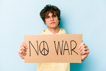Young caucasian man holding no war placard isolated on blue background