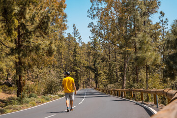 A young man walking along the forest road on the way up to Teide Natural Park in Tenerife, Canary Islands