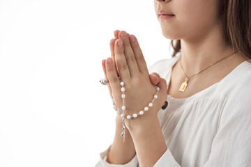 Girl in white dress holding a rosary and praying