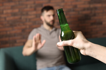 Man refusing to drink beer indoors, closeup. Alcohol addiction treatment