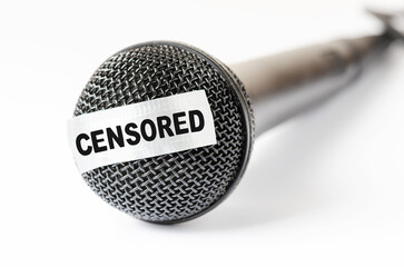The microphone is sealed with sticky tape. The concept of restricting freedom of speech or obscene language. Closeup, white background.
