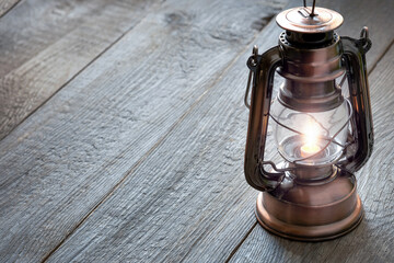 old kerosene lantern with burning light, antique vintage lamp on wooden table