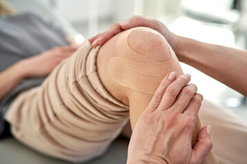 Physical therapist applying kinesio tape to the patient's knee