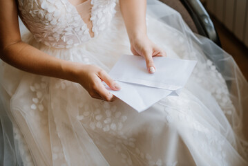 Bride sitting on sofa and reading a grooms letter. Closeup