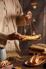 A moment of apocathery measuring ginseng in gold scale with chinese traditional medicine in wooden...