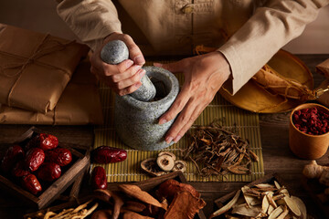 Front view of apocathery putting ingredient into mortar and pestle with chinese traditional...