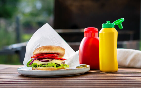 burger with meat cheese and vegetables with two bottles
mustard ketchup outside
