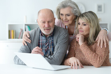 Portrait of two senior women and man using laptop