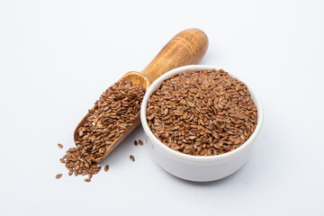 Flaxseed in white bowl and wooden spoon on white background